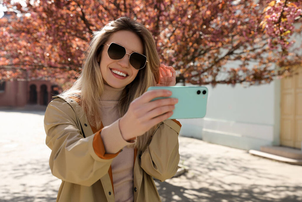 Young woman taking selfie on city street - Photo, image