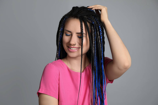 Beautiful young woman with nose piercing and dreadlocks on grey background - Foto, immagini