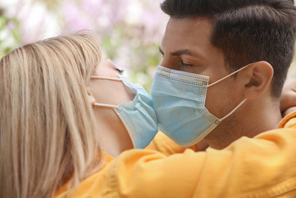 Couple in medical masks trying to kiss outdoors - Photo, image