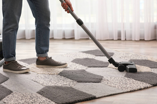 Man cleaning carpet with vacuum cleaner at home, closeup - Φωτογραφία, εικόνα