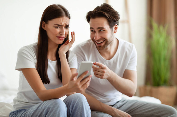 Geloso marito mostrando barare moglie telefono accusando di infedeltà indoor - Foto, immagini