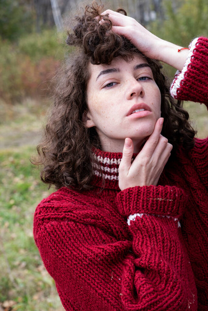 Girl in a knitted men's sweater against the background of an autumn forest - Foto, afbeelding