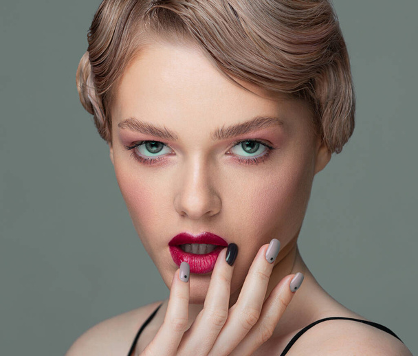 Close-up portrait of a woman. The fingers touch the lips. Well-groomed manicure. Red lipstick. Vintage hairstyle. Retro style. - Fotó, kép