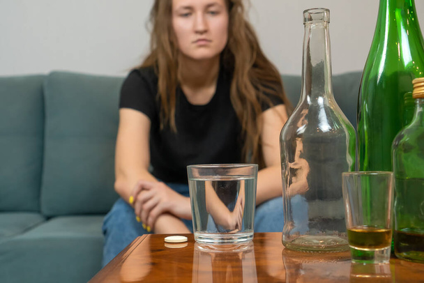 Young dark-haired woman with a hangover will drink a fizzy pill from her head after a wild party at home, trying to prepare for the day ahead. Concept of Monday morning, morning after drinking alcohol - Fotoğraf, Görsel