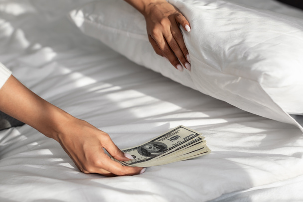 Black woman hiding money under pillow at home - Фото, зображення