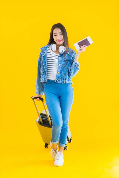 Retrato hermosa joven mujer asiática de viaje y ocio con bolsa de equipaje y pasaporte, tarjeta de embarque sobre fondo aislado amarillo - Foto, imagen