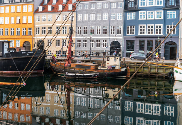 Copenhague, Dinamarca 26 de junio de 2019: Uno de los lugares más populares de la capital danesa es el Nyhavn (New Harbor). Vista del paseo marítimo con casas coloridas y amarre y barcos. - Foto, imagen