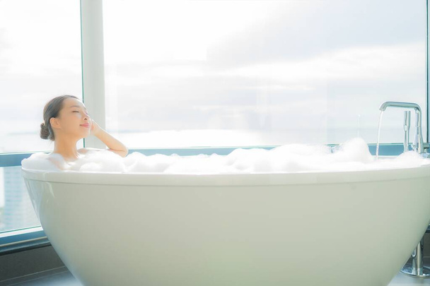 Retrato hermosa joven asiática mujer relajarse disfrutar en bañera en baño interior - Foto, Imagen