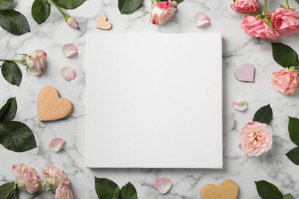 Flat lay composition with blank canvas and beautiful roses on white marble background. Mockup for design - Фото, изображение