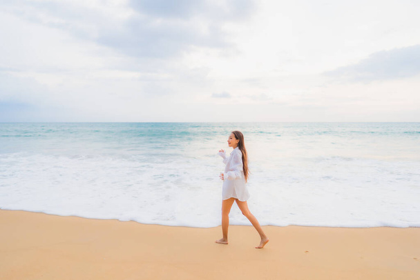 美しい若いアジアの女性の肖像旅行休暇で屋外ビーチの海の周りのレジャーをリラックス - 写真・画像