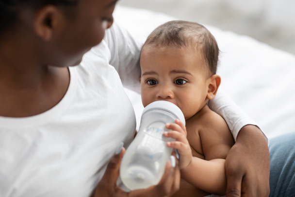 Афроамериканка кормит своего ребенка из детской бутылочки - Фото, изображение