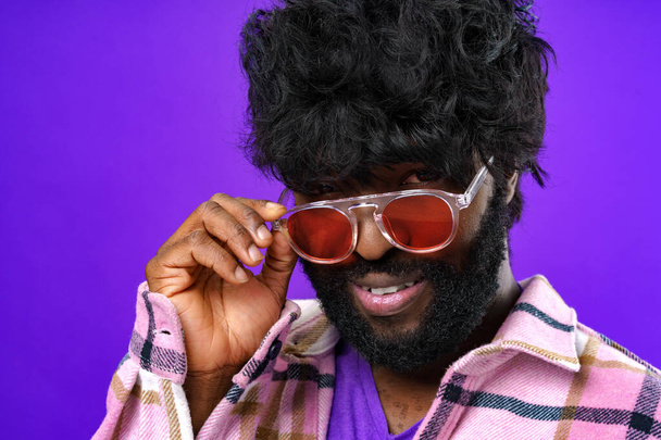 Fashion portrait of african american man in glasses against purple background - Фото, зображення