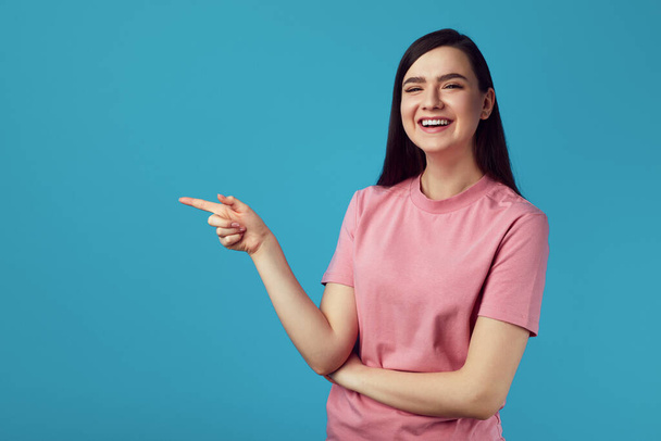 Modelo feminino caucasiano feliz indica com dedo indicador no espaço de cópia em branco - Foto, Imagem