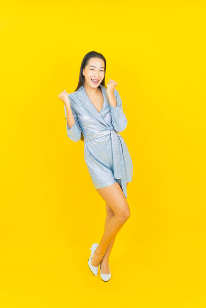 Portrait belle jeune femme asiatique sourire avec action sur fond de couleur jaune - Photo, image