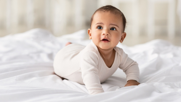 Cute little African American baby crawling on bed at home - Foto, imagen