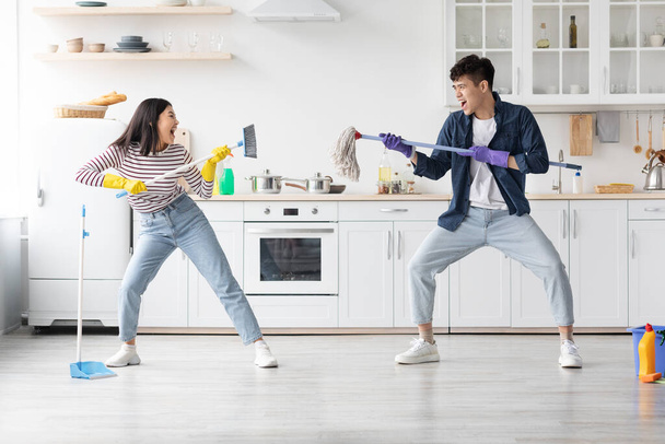 Crazy asian young couple having fun while cleaning apartment - Fotografie, Obrázek