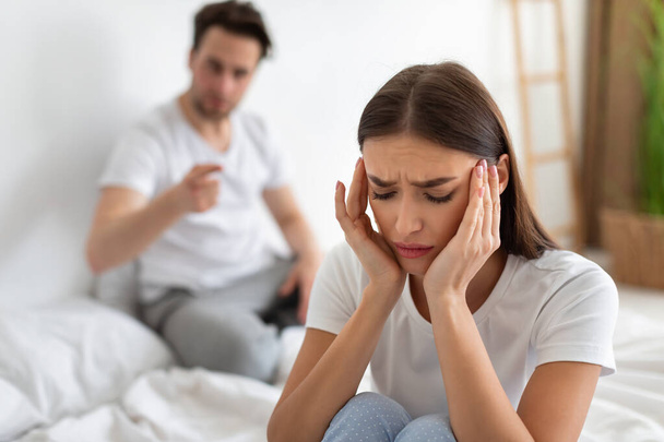 Wife Listening To Husbands Accusations Having Quarrel Sitting In Bedroom - Foto, Imagen