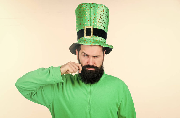 Turning his moustache upwards. Hipster in leprechaun hat and costume. Irish man with beard wearing green. Happy saint patricks day. Bearded man celebrating saint patricks day - Photo, image