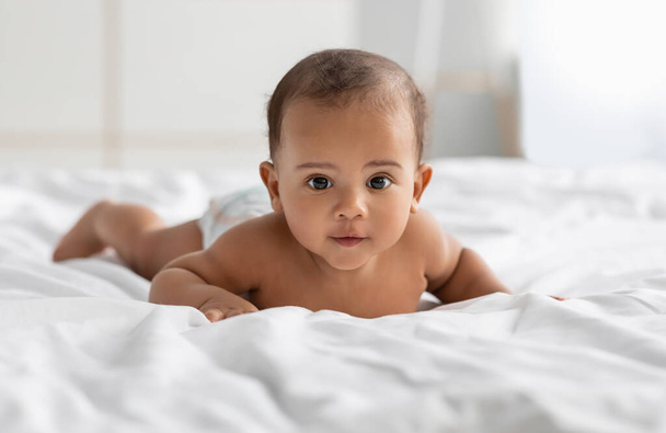 Cute little African American infant lying on bed - Zdjęcie, obraz
