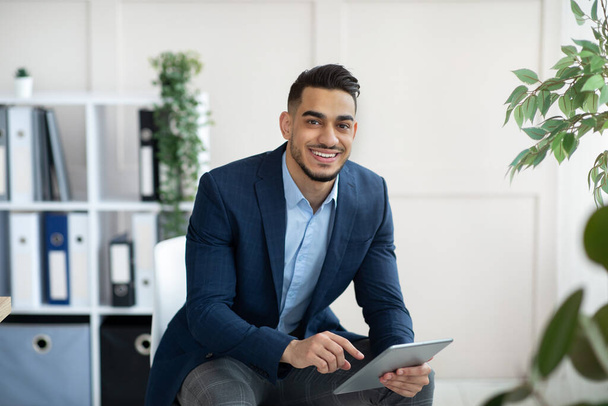 Hezký arabský podnikatel ve formálním obleku pomocí tabletu PC na pracovišti, prohlížení webových dokumentů v kanceláři - Fotografie, Obrázek