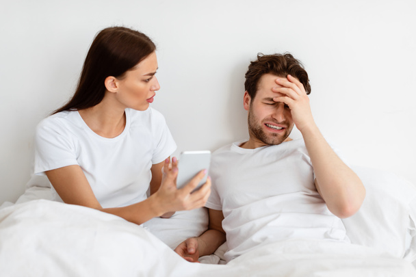 Zazdrosna żona pokazuje zdradzającego męża jego telefon domaga się wyjaśnienia w domu - Zdjęcie, obraz