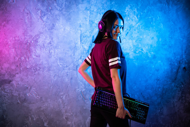 Joven adolescente gamer usando gafas de pie posando con equipo de juego de ordenador - Foto, imagen
