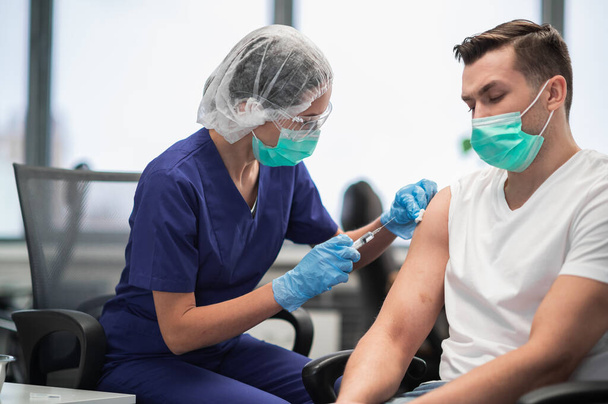 A kórház laboratóriumában egy nővér injekciót ad be egy férfi beteg karjába. - Fotó, kép