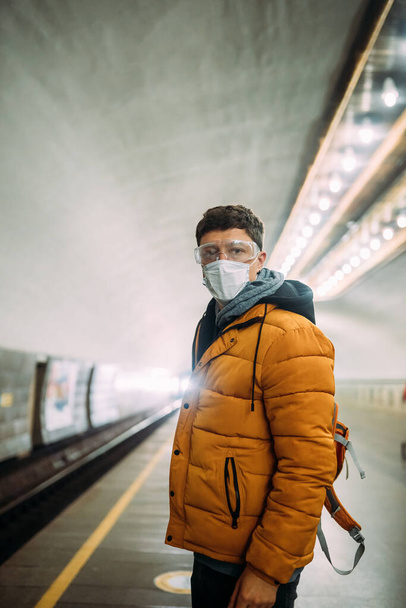 Guy standing at station in medical protective mask on his face. - Фото, зображення