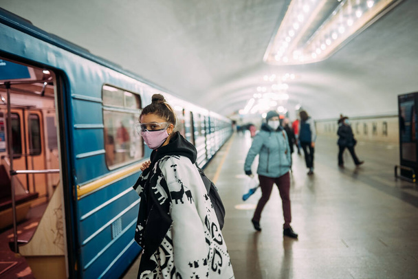 Young woman standing at station in medical protective mask - Foto, afbeelding
