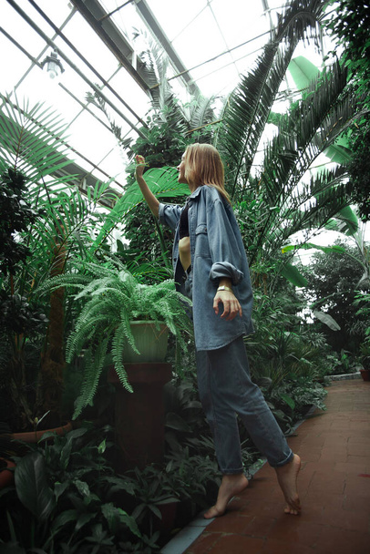 Beautiful young blonde girl portrait outdoors in a botanical garden among exotic plants. - Foto, Bild