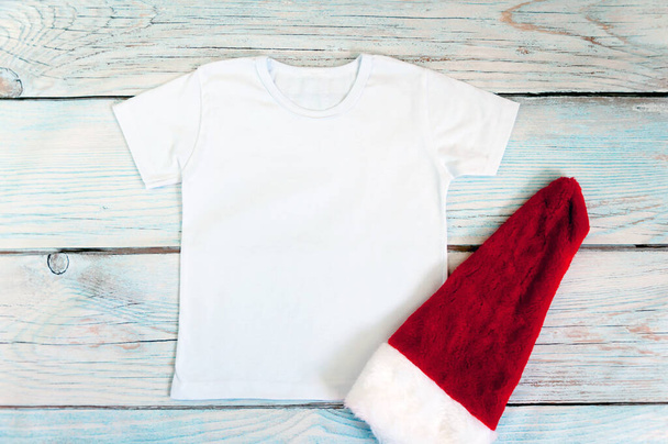 Christmas kid shirt mockup - weißes T-Shirt auf hölzernem Hintergrund. Archivbild. - Foto, Bild