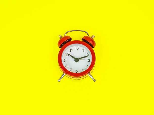 Reloj despertador rojo sobre fondo amarillo con espacio de copia - Foto, imagen