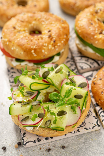シードベーグル、サラダ、グレーのコテージチーズと新鮮な健康的なサンドイッチ - 写真・画像