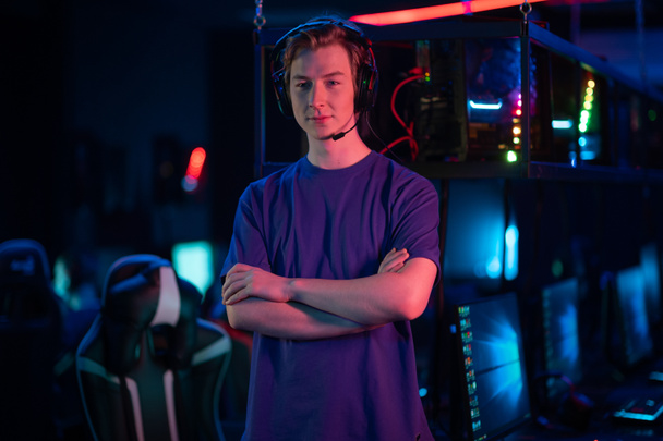 Before the start of the cyber tournament, a young player poses against the background of his teams playing places - Foto, afbeelding
