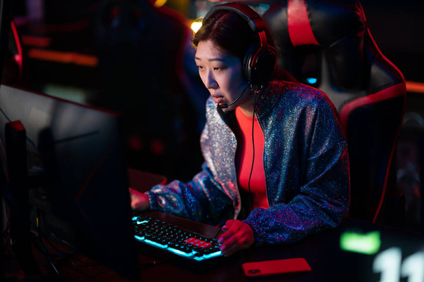Training von esports Spielern in einem Bootcamp. Ein junger asiatischer Spieler an einem leistungsstarken Gaming-PC blickt auf den Monitor. Online-Cybersport. - Foto, Bild