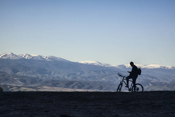 Dağlarda bisiklet süren bir adamın silueti.  - Fotoğraf, Görsel
