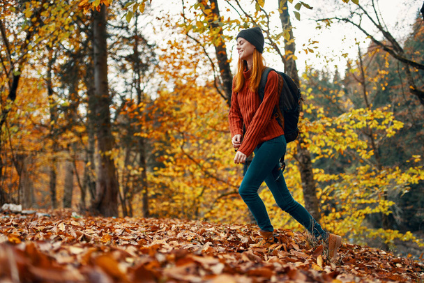 beautiful woman with a backpack in the park on nature landscape fallen leaves bottom view - Photo, Image