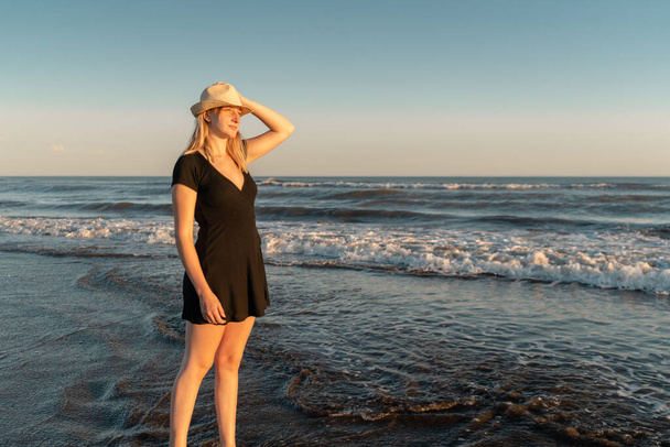 Kumsalda genç ve güzel bir kadın gün batımını izliyor..  - Fotoğraf, Görsel