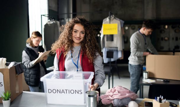 Woman volunteer working in community charity donation center, looking at camera. - Foto, imagen