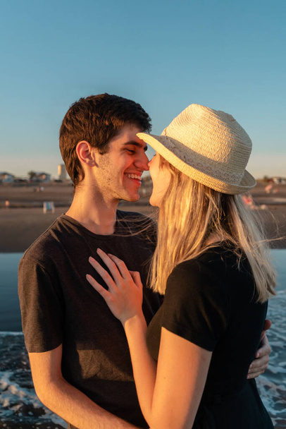 Les jeunes couples se regardent amoureux sur la plage au coucher du soleil. Plan vertical. - Photo, image