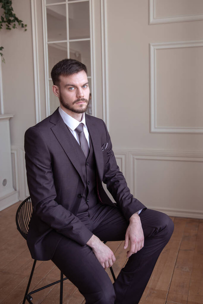 beautiful young man with a beard brunette model. guy in a classic suit in a light stylish interior. groom. portrait - Photo, image
