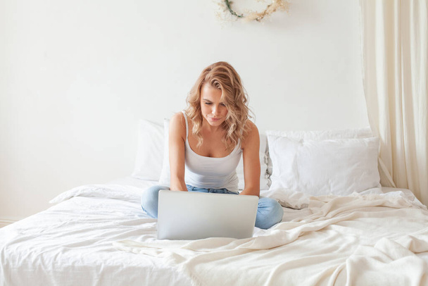 Young pretty blonde woman sit indoors at home using laptop computer - Foto, afbeelding