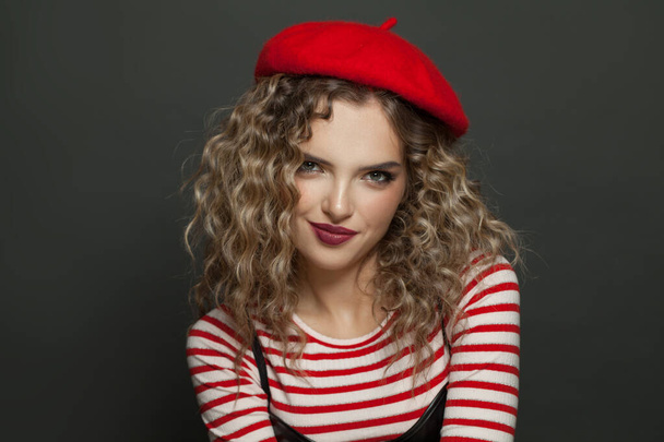 Красивая улыбающаяся французская модель в красном берете на черном фоне - Фото, изображение