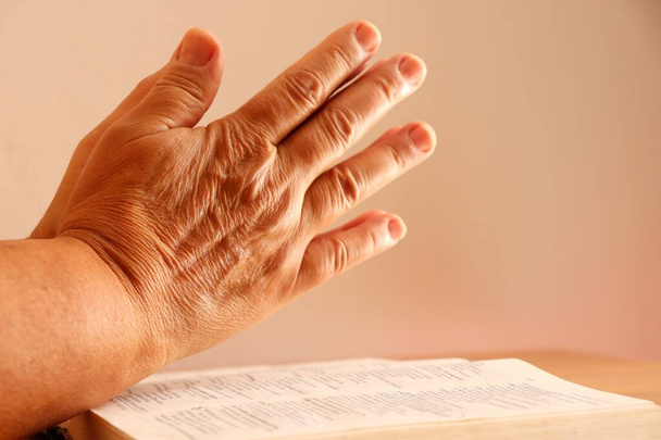 Idős Asszony kezek a Bibliára. Imádkozó kezek a Szent Biblia felett. A hit fogalma. - Fotó, kép
