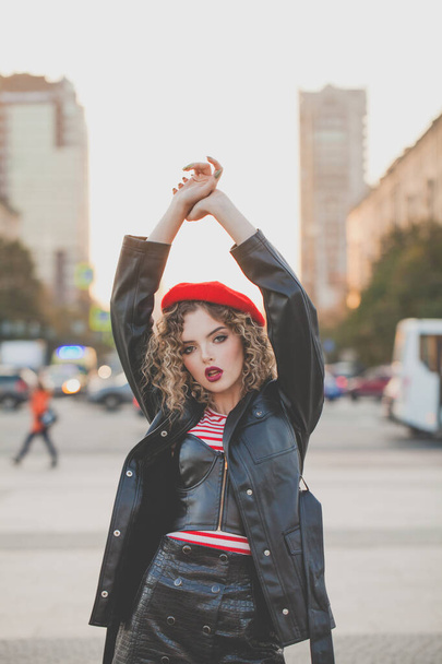 Fashion model woman with red lips makeup and curly hairstyle posing on city street - Fotoğraf, Görsel