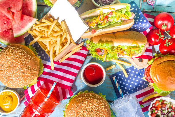Fourth of July, Memorial Day, USA Independence Day concept. Patriotic, American traditional food. Picnic party with watermelon, burgers, hot dogs, drinks, blue wooden outdoor table background - Foto, Imagem