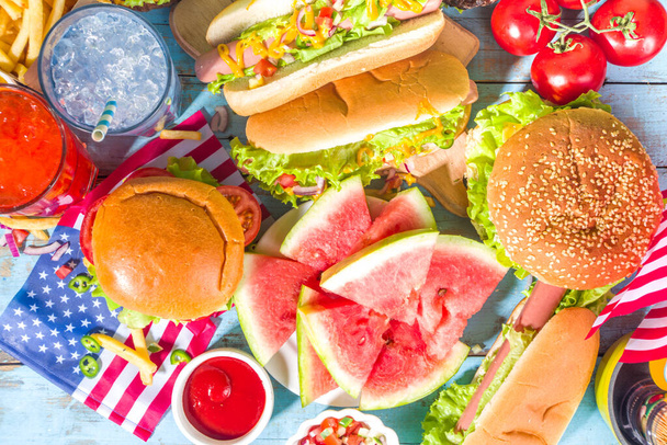 Neljäs heinäkuuta, Memorial Day, USA itsenäisyyspäivä käsite. Isänmaallinen, amerikkalainen perinteinen ruoka. Piknik puolue vesimeloni, hampurilaiset, hot dogs, juomat, sininen puinen ulkona pöytä tausta - Valokuva, kuva