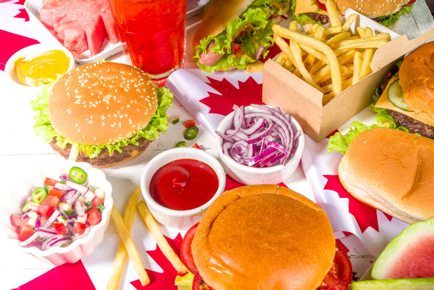 Zestaw różnych kanadyjskich potraw bbq Day. Stolik piknikowy z arbuzem w kształcie liścia klonu, flagi, hamburgery, hot dogi, frytki i sosy, zimne napoje, biały stół z czerwonym wystrojem, przestrzeń do kopiowania z widokiem z góry - Zdjęcie, obraz