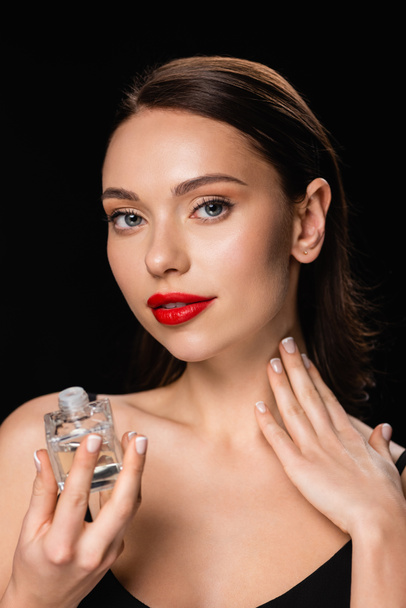 pretty woman applying perfume on neck isolated on black - Fotoğraf, Görsel