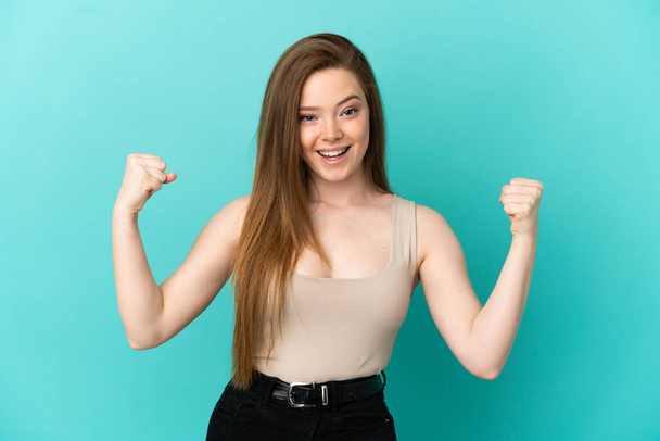 Teenager girl over isolated blue background celebrating a victory in winner position - Photo, Image